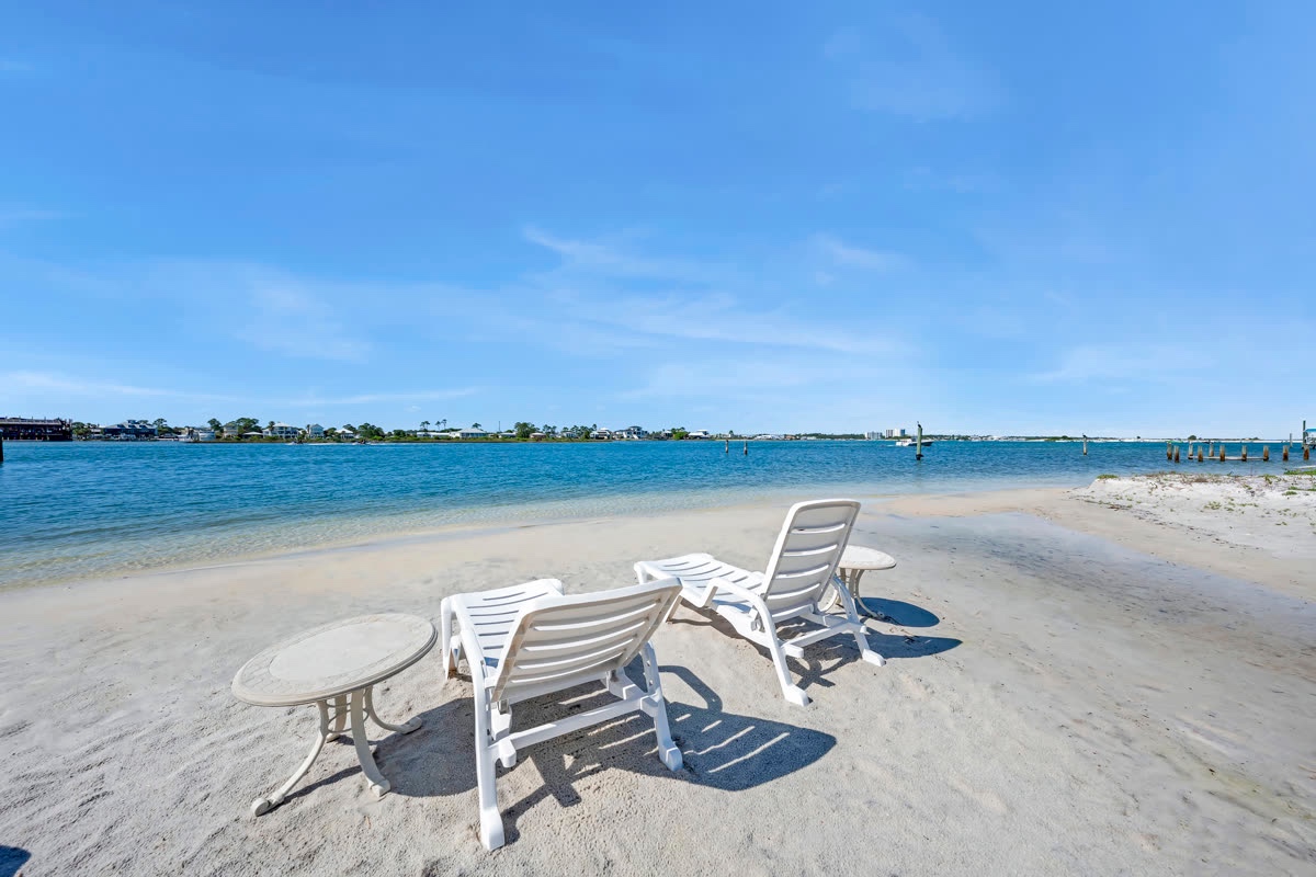 White Adirondack chairs on the sand by the Gulf
