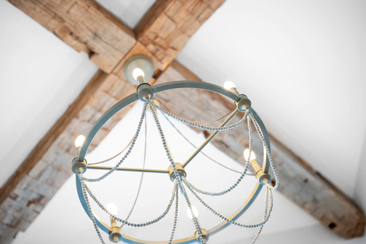 Vaulted ceiling with exposed wood beams and a globe chandelier