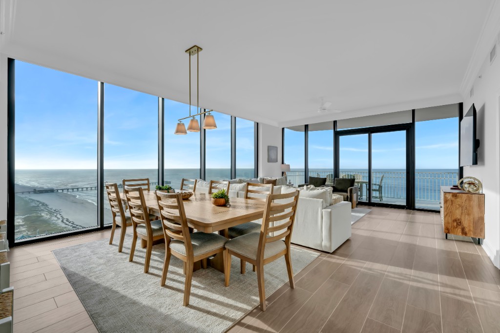 Oceanfront condo dining and living room with floor-to-ceiling windows overlooking the beach and pier